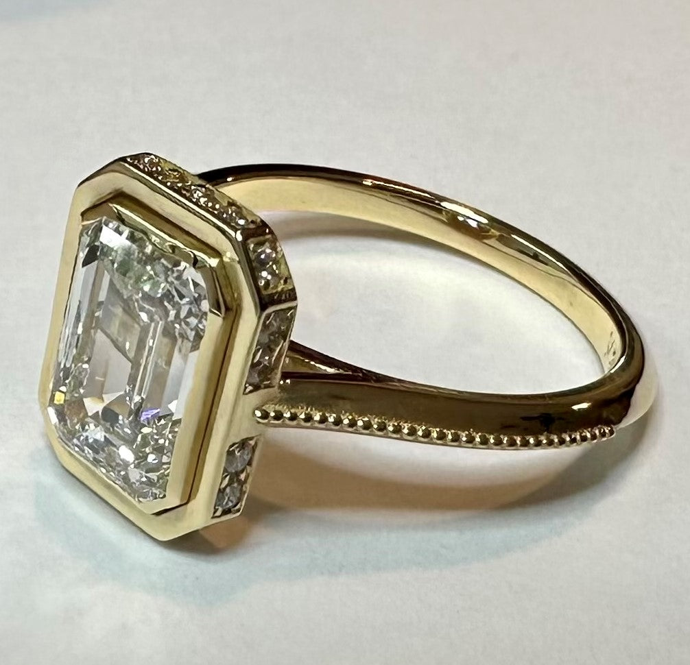 2.28ct lab grown emerald cut diamond, F color, VVS2 clarity, excellent cut grade, IGI cert. Set in a customer cad design 18k yellow gold diamond ring setting with .15cts of round brilliant side diamonds. Size 6.25